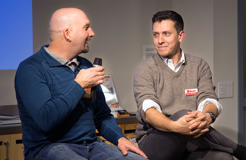 Charlie Mulligan of GiveGab holds a microphone and addressed Nick Nikitas of Rosie at during a panel discussion.