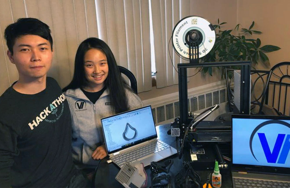 Longsha Liu and Kristen Ong of Vita Innovations pose with laptops and equipment for their innovation.